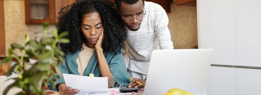 Jeune couple regarde des factures et un laptop avec un air découragé